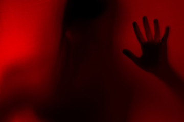 Blurred Woman's hand shadow asking for help. Horror and domestic violence concept in red