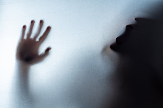 Blurred Woman's hand shadow asking for help. Horror and domestic violence concept