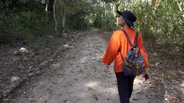 Mature woman inspecting the walls of the Acropolis at Ek Balam archaeological park in Yucatan, Mexico.