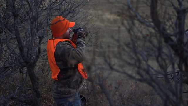 Hunter Stands and Looks through Binoculars. Handheld Slow Motion. 4K