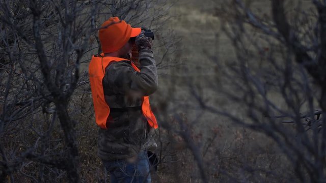 Hunter Stands and Looks through Binoculars. Handheld 4K