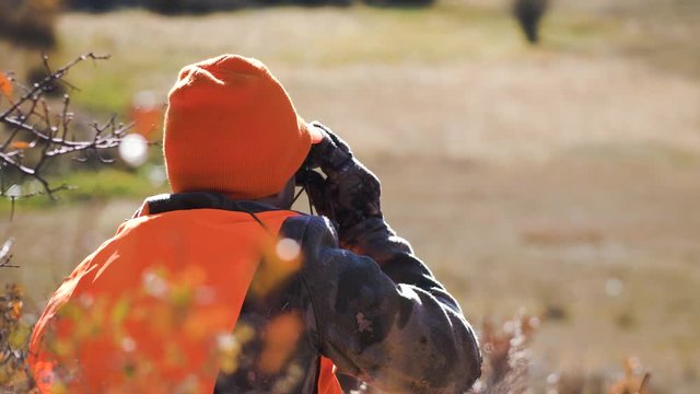 Hunter looks through binoculars. Long Lens Medium Close Up. 4K