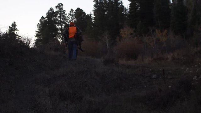 Father and Son Hunters walk up trail in early morning light. Handheld Slow Motion. 4K