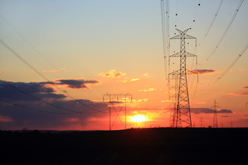 Fototapeta Słupy wysokiego napięcia, przemsył energetyczny, piękny kolorowy zachód słońca.	 obraz