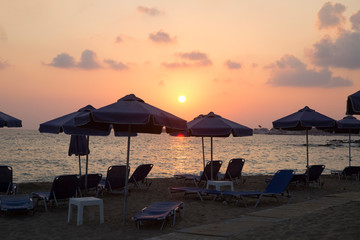 Sunset on the beach with umbrellas and sunbeds. There is nobody on the beach. SODAP Beach, Paphos, Cyprus