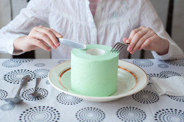 A roll of toilet paper lies on a plate. Girl wants to eat it with a knife and fork.