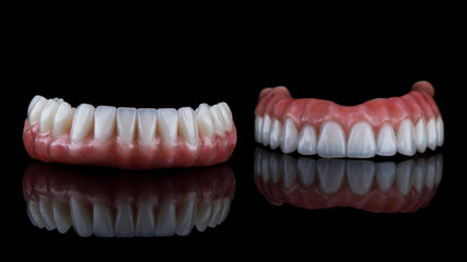 beautiful dental prosthesis for the lower jaw in the foreground, shot on a black background with reflection