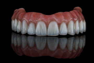 very effective dental prosthesis for the upper jaw on black glass with a beautiful reflection