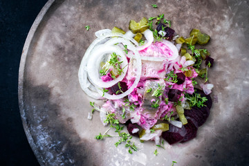 Traditional matie herring with beetroot salad and onion rings offered as top view on a rustic...