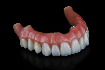 high-quality dental prosthesis for the upper jaw with a pink gum on a black background