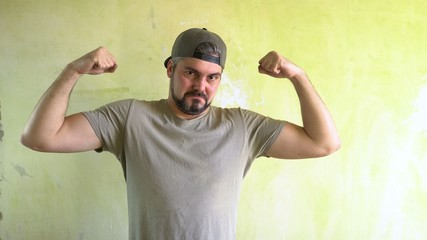 Naklejka premium A man by the wall shows biceps. Athlete in the gym. Sportsman. Healthy lifestyle.