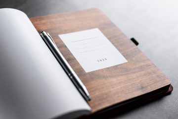 Open personal calendar for 2020 year, lay on table with pen. Copy space. Wooden pattern page with to do list.