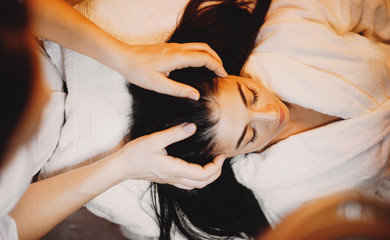 Upper view portrait of a brunette caucasian woman lying on the couch while having a head massage...