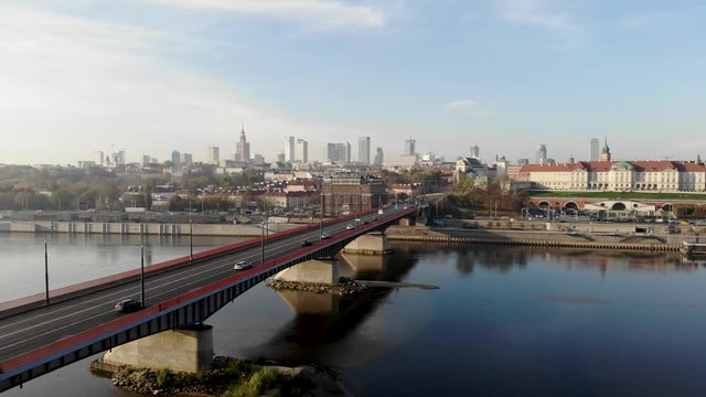 Panoramic aerial shot of Slasko-Dabrowski bridge, downtown and the Royal Castle in Warsaw, Poland at the beautiful, sunny day. Cinematic drone shot of cars, trams and buses passing by the river