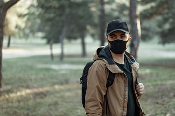 Young man in medical mask walking in park 
