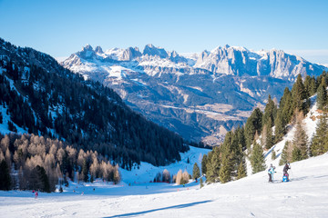Sunny winter landscape at Ski Area in Dolomites, Italy - Alpe Lusia. Ski resort in val di Fassa near Moena. Winter Dolomites and blue sky. Aerial view on ski slopes