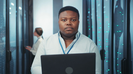 Portrait of handsome african IT specialist using tablet working in digital network and data center...