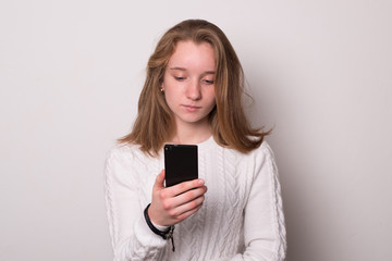 Fototapeta premium Cute girl holding a smartphone. Positive caucasian teen girl with smartphone.