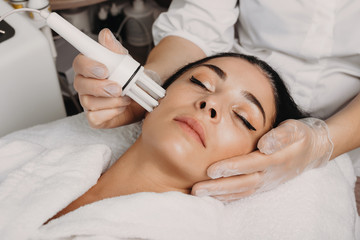 Obraz na płótnie Canvas Facial anti aging procedure done at the salon on the face of a brunette caucasian lady
