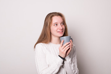 Positive girl holds a mug of tea. Teen girl drinks from a mug.