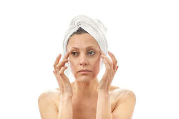 A beautiful middle-aged woman looks after her face. Makes facial skin massage. Isolated white background.