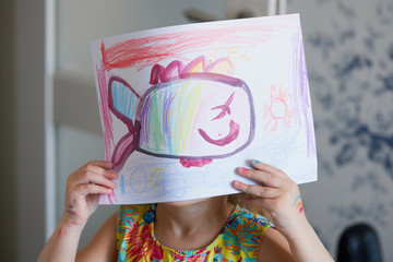 Childrens creativity. Little child girl draws with wax pencils at home. The concept of distance...