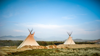 Dos tipis en la montaña bajo un cielo azul © William