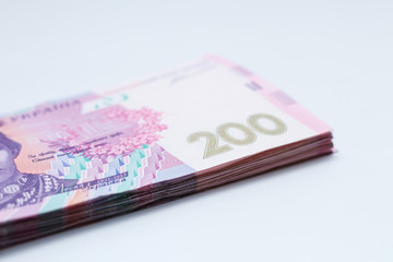 A lot of new banknotes in denominations of 200 Ukrainian hryvnias isolated on a white background with shadow. European money exchange. Ukraine currency. Selective focus