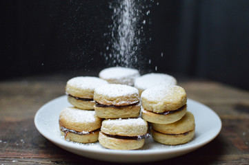 Vanilice, traditional serbian vanilla cookies with jam and sprinkled powdered sugar on the white plate