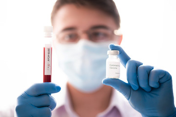 Blood test tube and vaccine in male hand close up, doctor in medical mask. Concept of vaccination,...