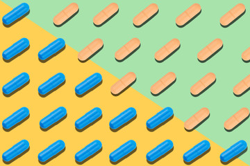 Seamless pattern with blue and orange pills on yellow and light green background.