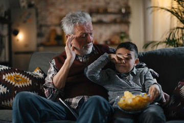 Grandfather and grandson watching television. Grandfather and grandson enjoying at home.	