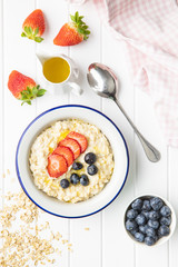 Bowl of oatmeal porridge with strawberries and blueberries.