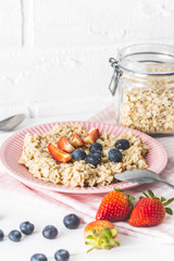 Plate of oatmeal porridge with strawberries and blueberries.