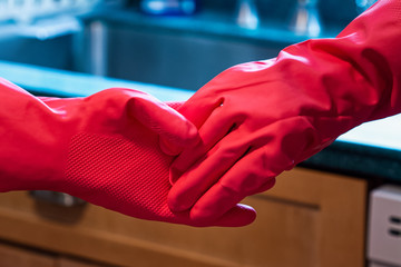 Two people hold latex-gloved hands in the kitchen