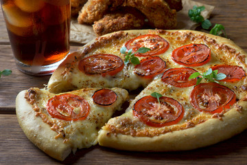 pizza Margarita with a glass of Cola and chicken wings on a wooden background