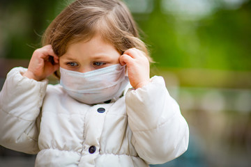 little girl on a walk in a medical mask