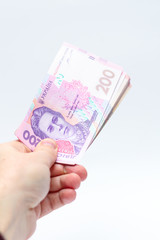 A banknote of 200 hryvnia in a male hand on a white background. Giving a bribe in Ukraine. European money exchange. Ukraine currency