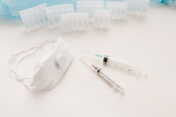 Medical ampoules with solution, syringes and protective mask respirator on the table