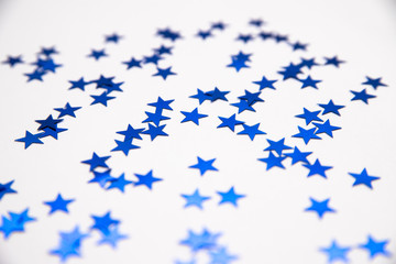 Blue sequins in the form of stars on a white background. New year's holiday and birthday. Background and texture.