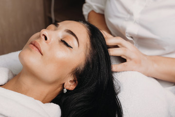 Fototapeta na wymiar Close up portrait of a caucasian woman with black hair lying on couch during a head massage procedure