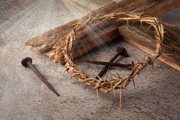Easter background depicting the crucifixion with a rustic wooden cross, crown of thorns and nails.