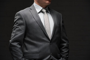 businessman portrait dressed in gray suit, dark wall background