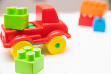 Children's construction kit with cubes and a red car on a white background. Children's entertainment. Development of hand motor skills. logic of thinking.