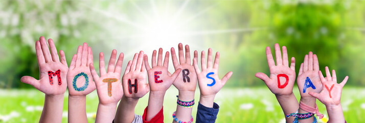 Children Hands Building Colorful English Word Mothers Day. Sunny Green Grass Meadow As Background