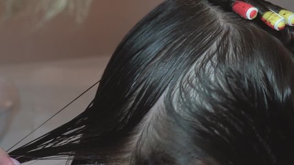 Curl hair on the curl. The hairdresser makes a hairstyle for a child by combing and twisting hair into a curl in a beauty salon.