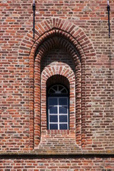 Fototapeta na wymiar Texture of a simple gothic window arch on the brick facade of the Oostkapelle church tower in the Netherlands