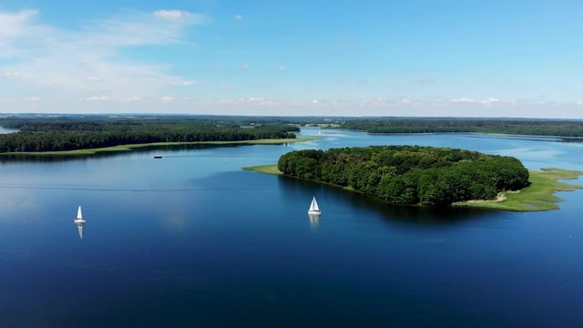 Aerial, panoramic view of sailboats on the beautiful lake Kisajno on a sunny day. Mazury by drone, Poland