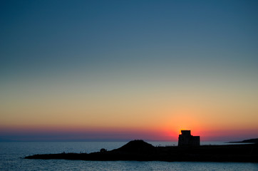 Tramonto al mare con scogliera e roccaforte