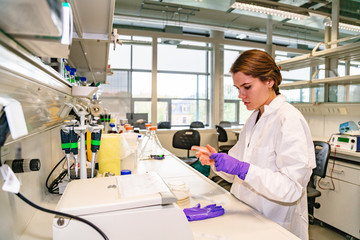 Girl scientist holds glass slide and examines it